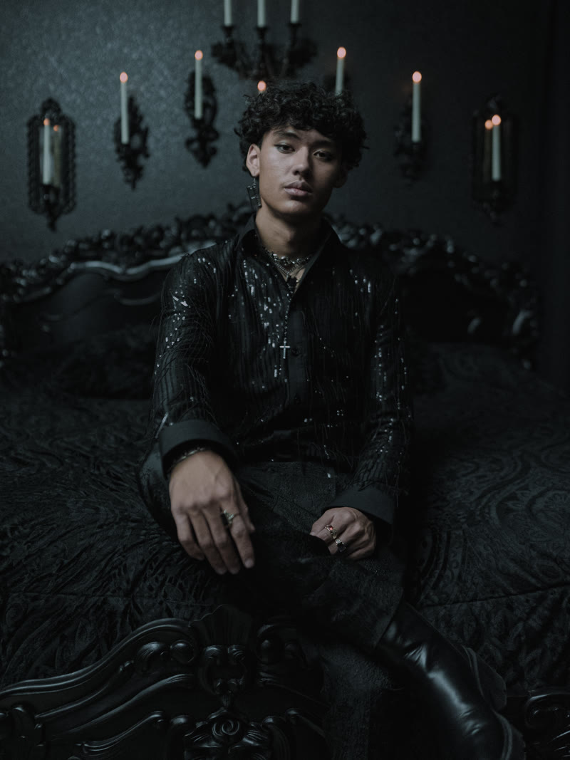 Seated on an ornate chaise in a dark room, Bete Noire fashion shoot