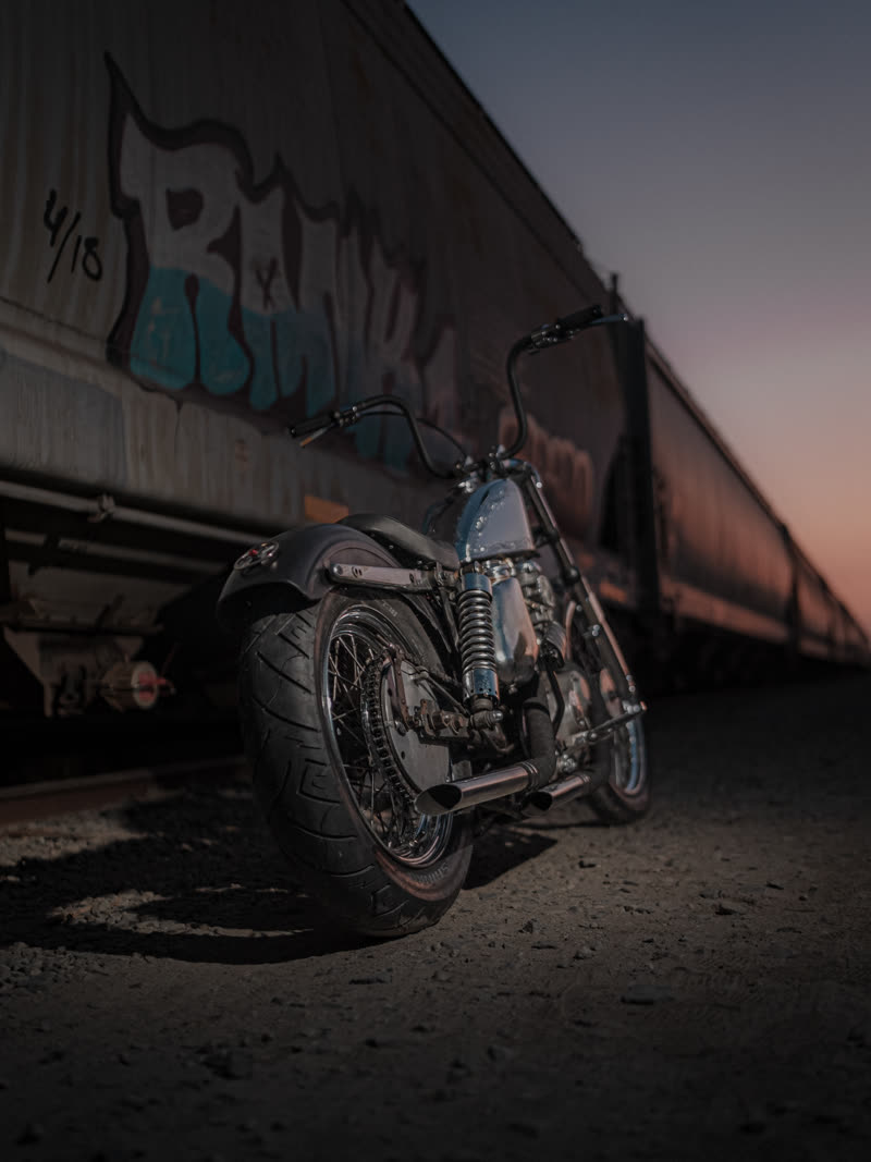 Chopper parked against a graffiti boxcar at dusk