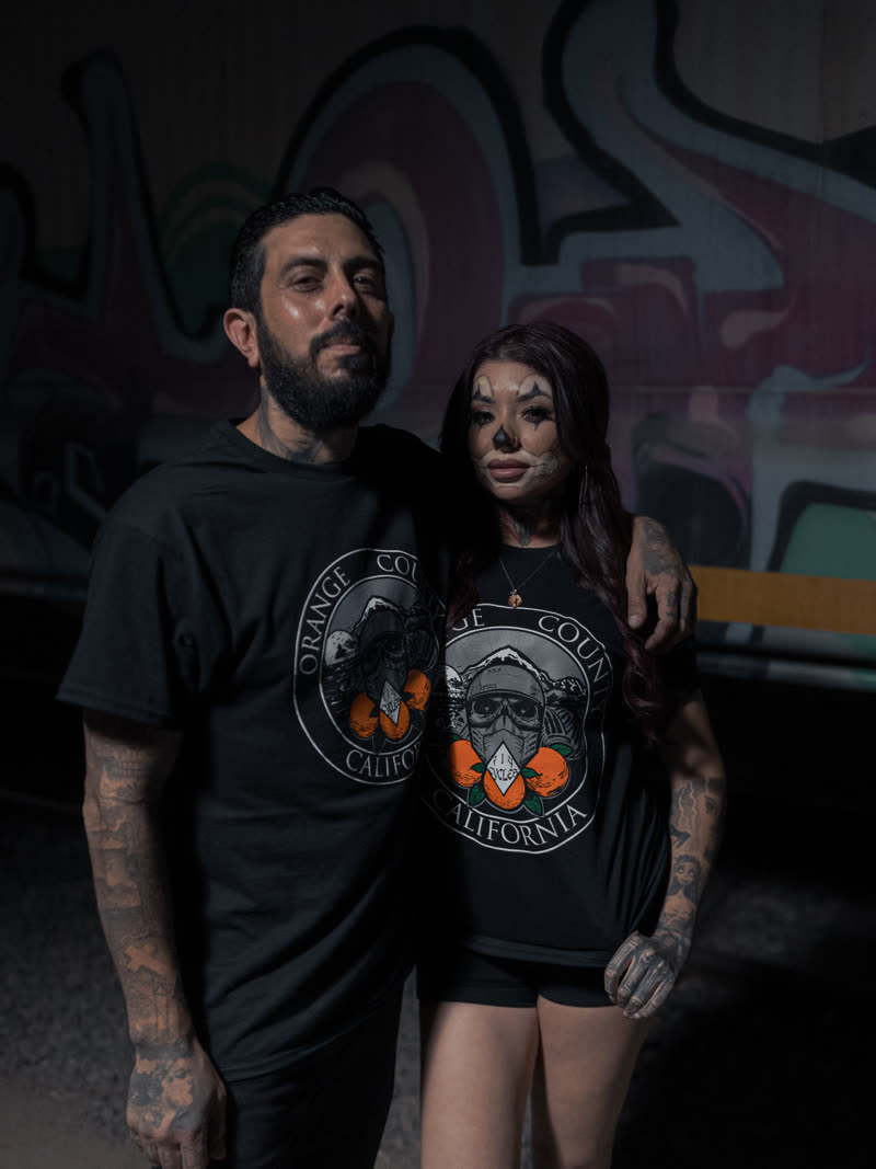 Couple photographed with hard flash against a graffiti wall
