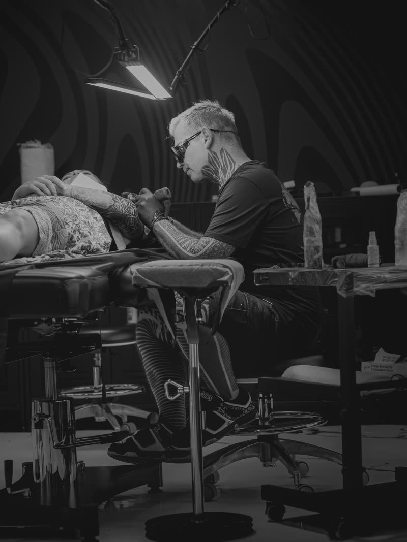 Wide of the studio mid-session, client on the table, black and white