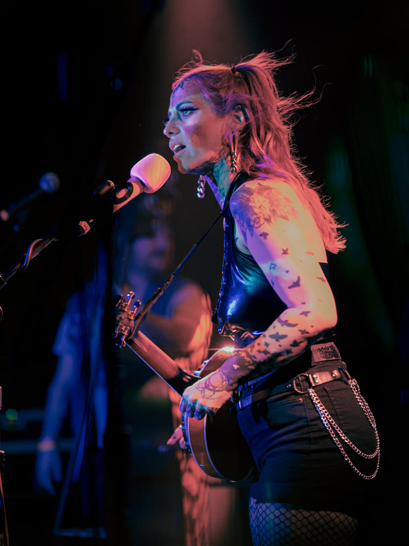 Libby of Bridge City Sinners at the microphone under blue stage light