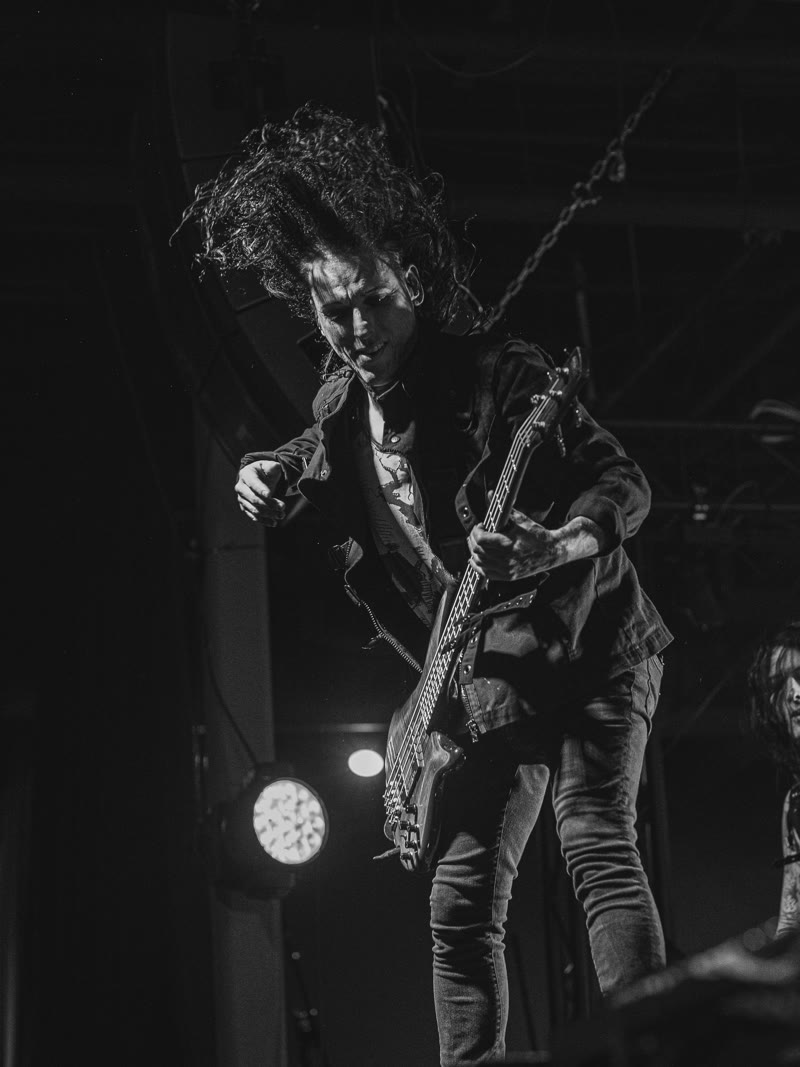 Guitarist bent over the neck, hair thrown forward, black and white