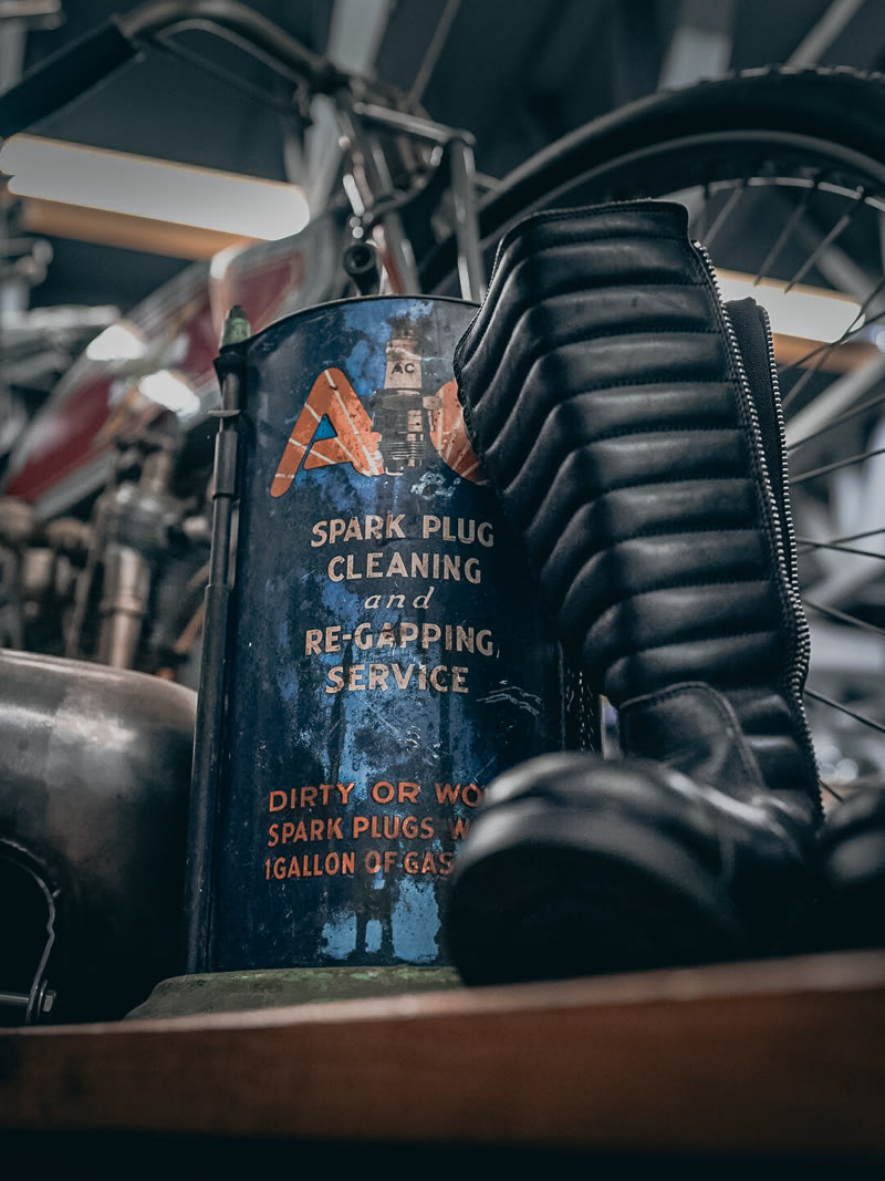 A spark plug service can on the bench, shop clutter behind