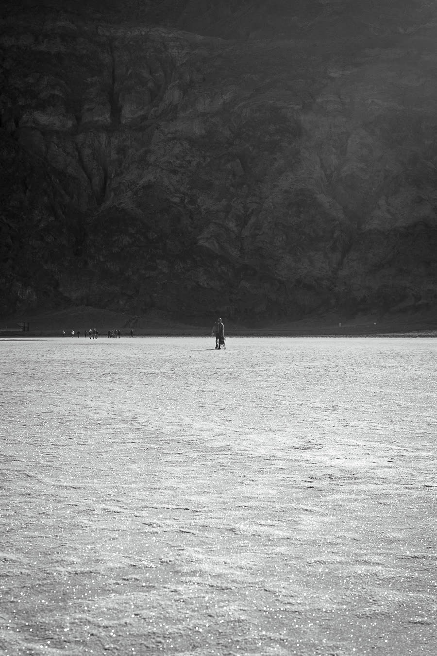 A figure crossing the salt, dwarfed by the range behind