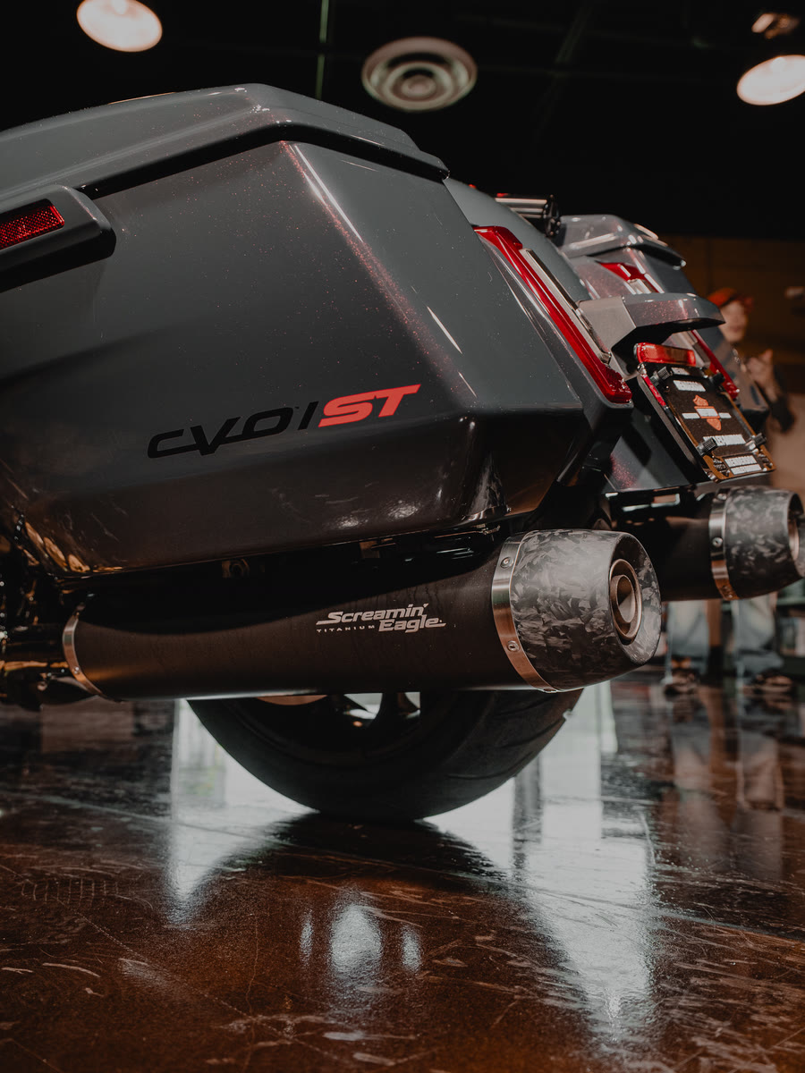 The gray CVO from behind, exhaust and bags over the wet showroom floor