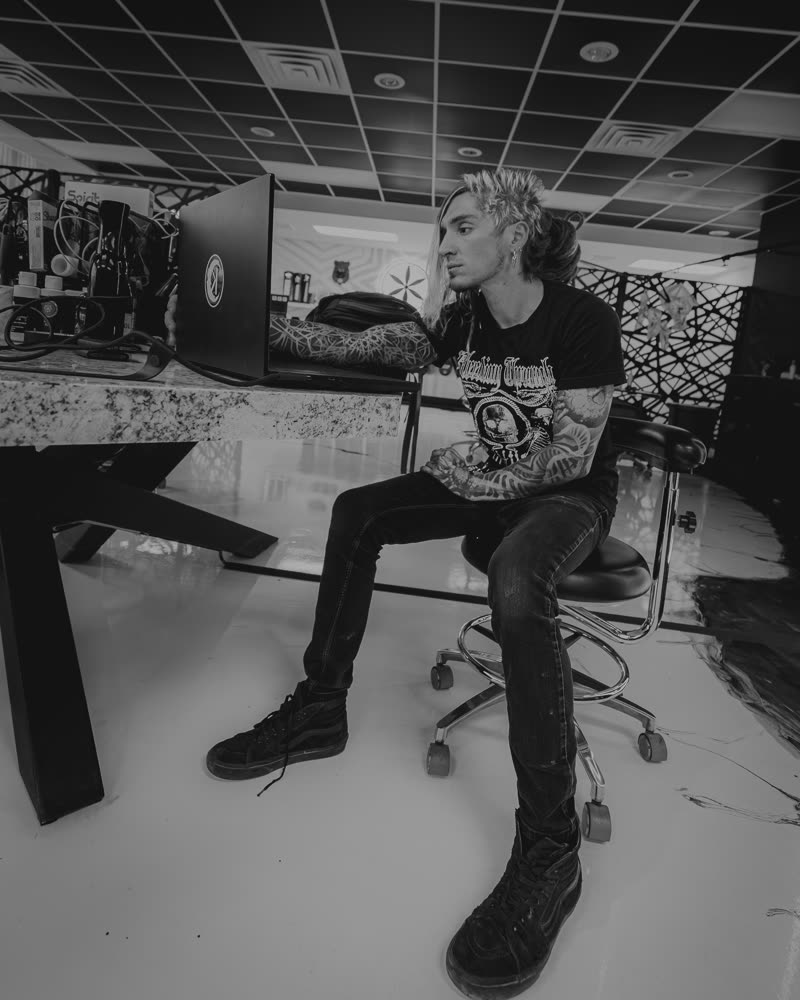 Ilya seated in the shop before a session, black and white