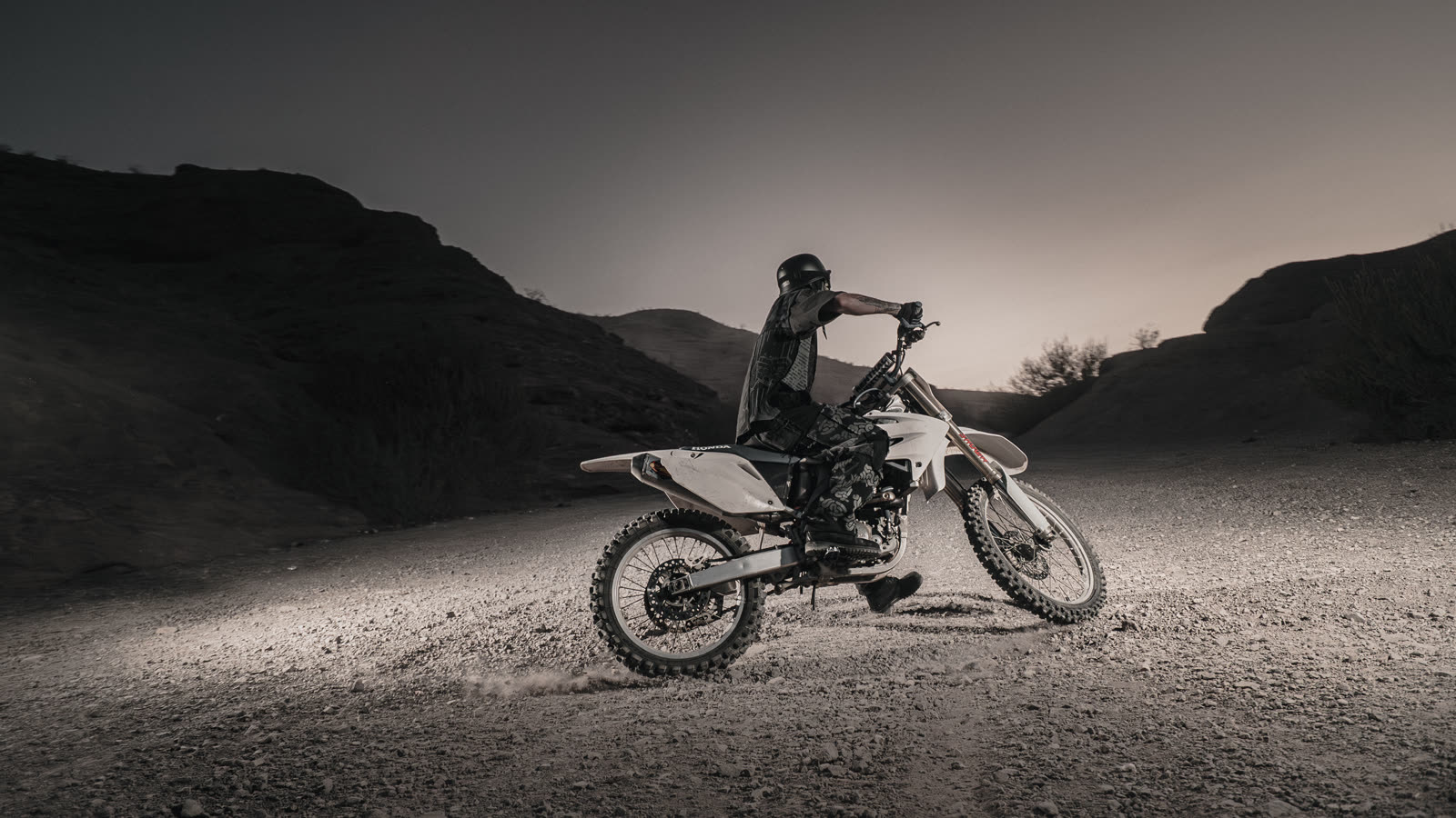Bike parked broadside on the ridge, backlit by the last sun