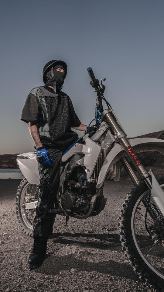 Standing over the bike, full outfit head to boot