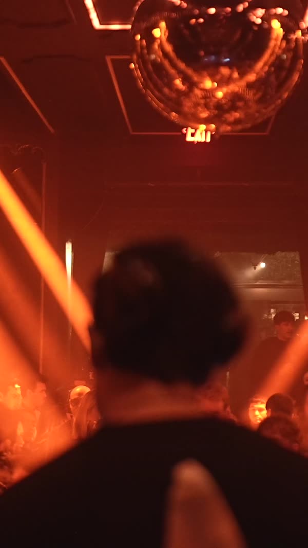 Packed floor under crossed amber beams at a Pieces night